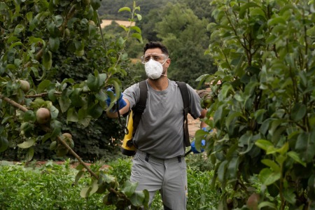 Trabajador en el campo usando mascarilla FFP2 MB25L, diseñada para filtrar partículas y proteger frente a contaminantes durante fumigación, combinando ajuste ergonómico, confort y alta eficacia de filtración